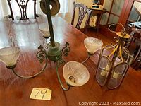 Green metal chandelier with 3 glass shades on a wooden table