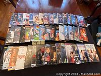 Photo showing around 42 used DVD movie cases arranged on two tables, various titles and artwork visible.