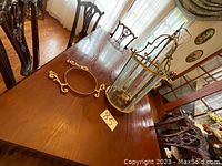 Octagonal glass and brass hanging lantern with mounting ring and decorative scroll brackets arranged on table.