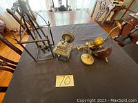 Two lighting fixtures on a black cloth-covered table: one red hanging lamp with gold hardware and one gold metal wall sconce with curved arm.