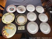 Top view of 11 assorted porcelain plates arranged on table showing varied patterns, colors, and sizes.