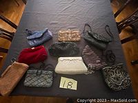 Nine antique purses displayed on a black surface, showing variety of colors, materials, and styles.