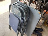 Photo showing one gray folding card table and four matching folding chairs stacked together, highlighting the materials and condition.