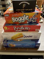 Stacked board games Punderdome, Boggle, Password 4th Edition, Pictionary Junior, and Chinese Checkers