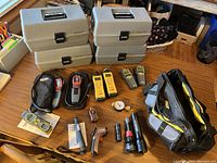 Four grey plastic radon test machine cases on wooden floor with various handheld inspection tools