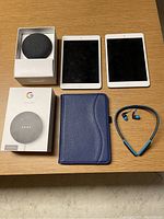 Two iPad Mini 2 tablets, Google Nest Mini in and out of box, blue tablet folio case, wireless neckband headphones