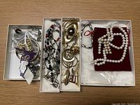 Photo showing multiple boxes with mixed vintage and handmade jewelry items including brooches, beaded necklaces, bangles, bracelets, and pearl necklace.