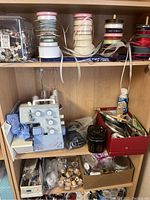 Shelf with Bernina Surger sewing machine, ribbons, thread spools, and sewing tools in boxes