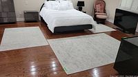 Two 6'x4' rugs and one 7'8"x5'3" rug laid out in bedroom showing relative sizes.