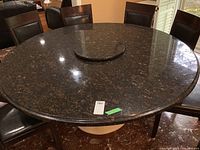 Top-down view showing round black granite surface with brown flecks and lazy Susan center feature. Ogee edge visible.