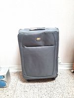 Front view of large gray soft-sided rolling luggage with front zippered pocket and VIA Rail Canada metal logo badge.