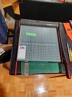 Top view of Premier paper cutter showing grid surface with measurement markings and wooden handle blade arm.