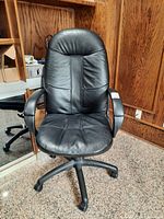 Front view of black leather task chair showing padded seat and backrest with some wear.