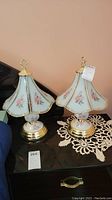 Pair of brass and glass bedside touch lamps on glass table with floral patterned lamp shades and brass bases