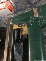 Close up of green air powered nailer showing trigger and brand label