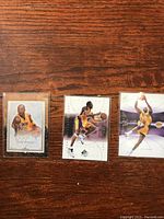 Three Kobe Bryant basketball cards front view on wooden surface