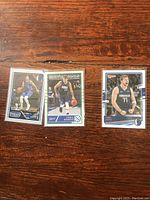 Overview photo of three Luka Doncic basketball cards laid out on wooden surface, each in protective plastic sleeve.