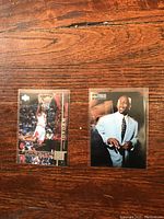 Photo of two Michael Jordan basketball cards face-up on a wood surface, showing one action shot dunking and one formal portrait.