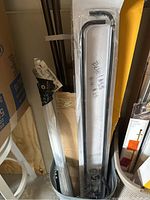 Multiple curtain rods in black metal and white, some with packaging and wall brackets visible