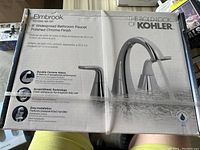 Box front showing KOHLER Elmbrook bathroom faucet with polished chrome finish and product features.