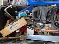 Black plastic bin filled with assorted hand and power tools including a Stanley handsaw, clamps, Magnetek box, and tool pouch