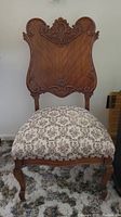 Front view of antique ornate wooden chair with brocade seat showing overall condition and design details