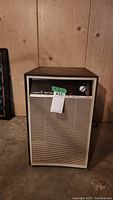 Front view of the beige and brown Westinghouse ECM20 dehumidifier showing its vent grill, control knob, and sticker with lot sticker attached.