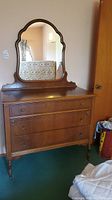 Front view of wooden dresser with three drawers and attached mirror showing drawer handles and wood grain detail.