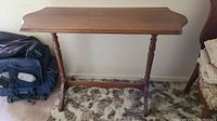 Full view of the vintage wooden side table showing rectangular top and spindle legs on carpeted floor.