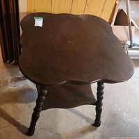 Full view of dark stained oak side table showing scalloped edges and barley twist legs.