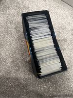 Top-down view of a box filled with numerous Pokémon trading cards packed upright showing edges and backs of cards.