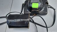 Black leather Yashica branded camera case with strap, showing embossed logo and snap closures.