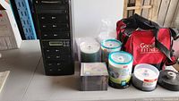 Photo of LG DVD duplicator tower and assortment of blank discs with cases and bag