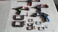 Overview of all clamps on table including trigger clamps, C-clamps, and bar clamps.