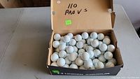 Box open showing approximately 110 used Titleist Pro V1 golf balls with some wear.
