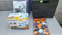 Photo showing 2 quilted pillows with bird designs, the Halloween tablecloth folded, Dressmaker II sewing machine box, and black folding cart