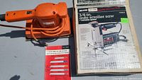 Orange electric sander with cord, red and white blade set package, Sears Craftsman jig saw box on surface