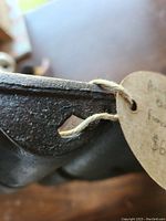 Close-up of corner of the cast iron bread mold showing wear, rust, and attached handwritten tag.