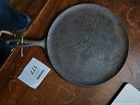 Top view of the antique cast iron crepe pan with handle showing worn and rusted surface.