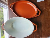 Top view showing the inside of both pot and lid with contrasting white enamel interior and orange exterior.