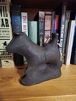 Solid cast iron horse-shaped mould piece shown on shelf with books behind