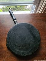 Another angle of the cast iron pan's underside emphasizing the embossed brand and location.