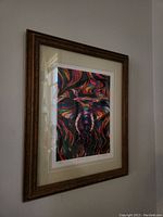 Framed fine art print seen from an angle showing colorful abstract elephant artwork and brown wood frame.