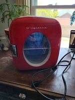 Front view of the red Frigidaire mini fridge with clear window and power cord visible