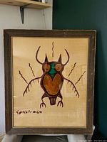 Front view of framed interior glass painting showing stylized owl and Inuk syllabic signature