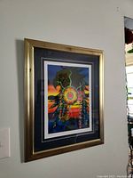 Side angled view of framed art showing gold frame and vibrant print including sunset and stylized eagle.