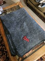Folded grey wool blanket on wooden table showing overall condition.