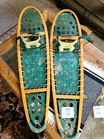 Pair of wooden frame snowshoes on glass-top table showing overall condition and design.