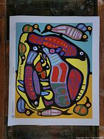 Full view of the colorful Norval Morrisseau print showing abstract figures in vibrant colors with black outlines and white border.