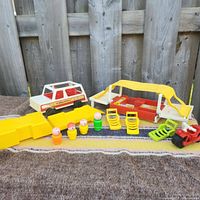 Photo of set laid out on the ground showing the camper trailer with yellow canopy, pickup truck, five Fisher Price figures, yellow ramp, folding chairs, and ATV toy.